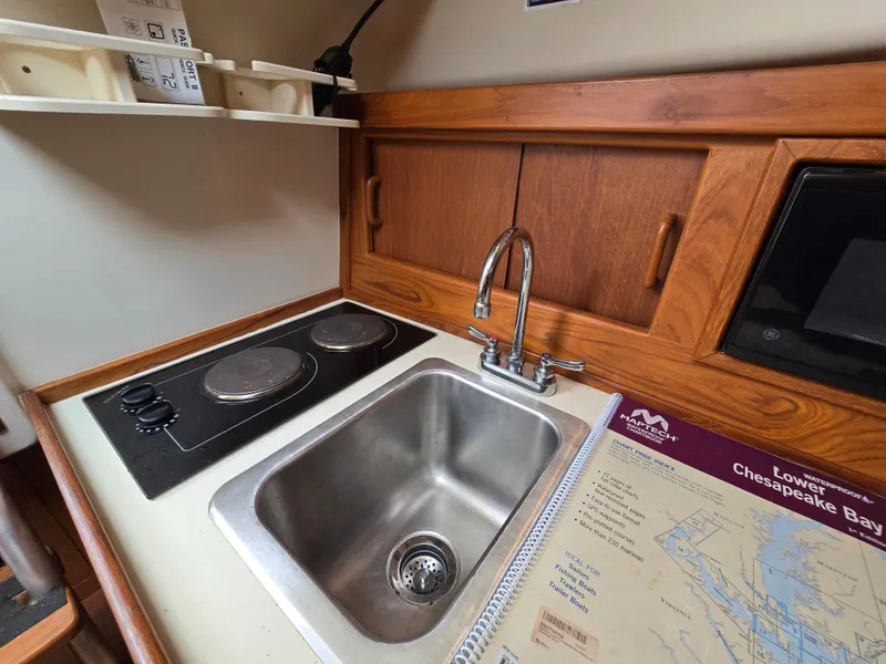 Slide: The Image of 2001 Mainship Pilot 30 Sedan kitchen with stove, sink, and Chesapeake Bay map. - 25