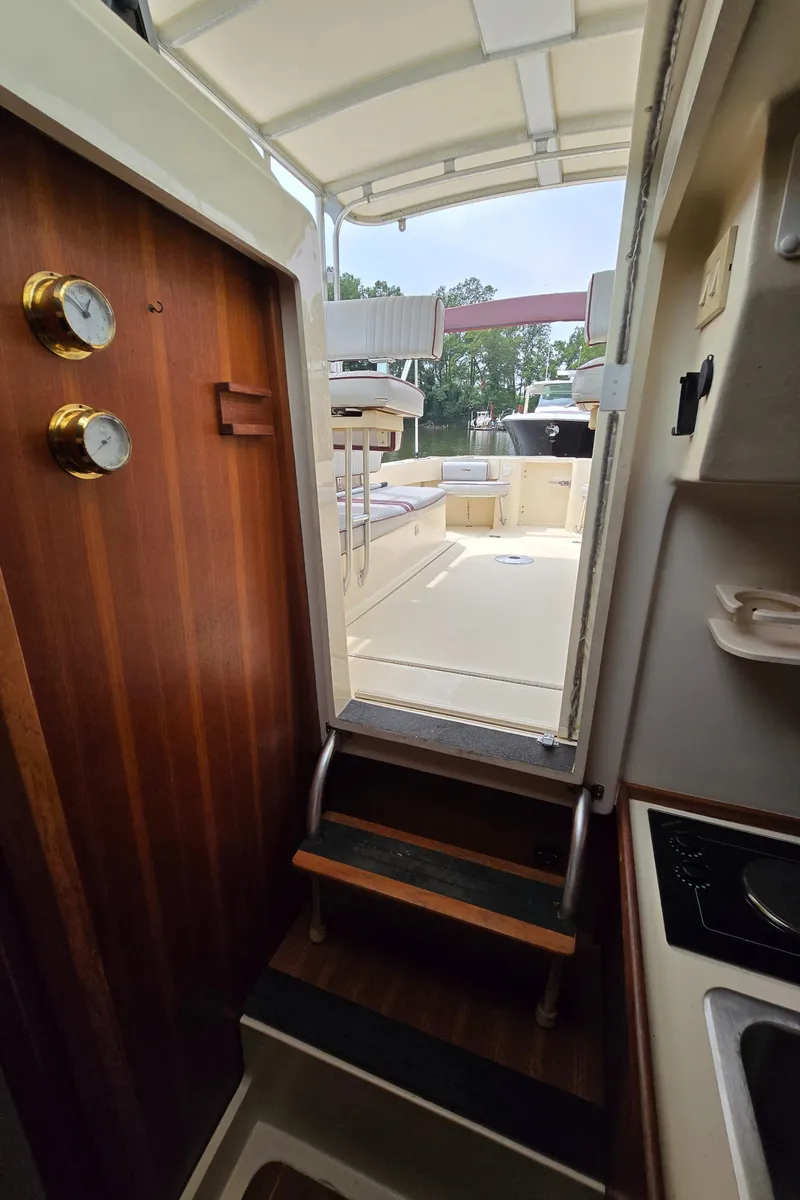 Slide: The Image of 2001 Mainship Pilot 30 Sedan interior with wooden door, steps, and outdoor seating area. - 45