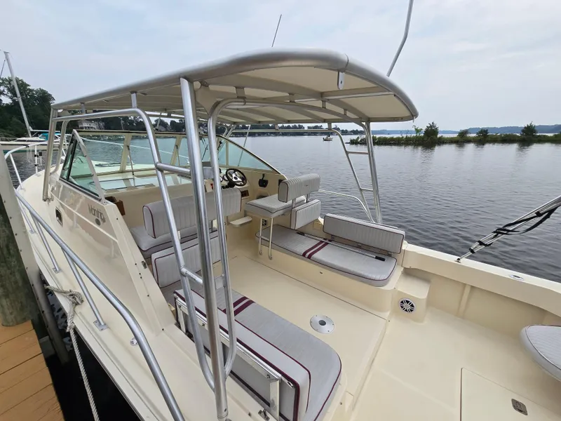 Slide: The Image of 2001 Mainship Pilot 30 Sedan boat docked, featuring spacious seating and canopy, on a calm lake. - 6