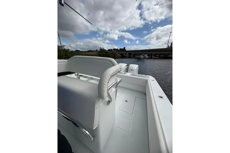 Slide: The Image of 2026 Contender 32 ST boat on water under cloudy sky, near a bridge. - 10