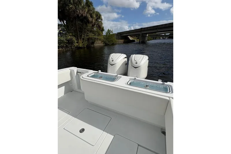 Slide: The Image of 2026 Contender 32 ST boat with dual engines, docked near a bridge on a sunny day. - 16