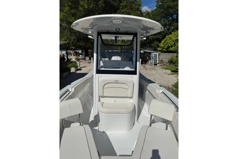 Slide: The Image of 2025 Sea Hunt Ultra 239 SE boat interior with seating and console, surrounded by greenery. - 15