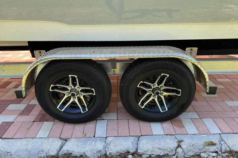 Slide: The Image of Trailer wheels of a 2025 Sea Hunt Ultra 239 SE on a brick driveway. - 24