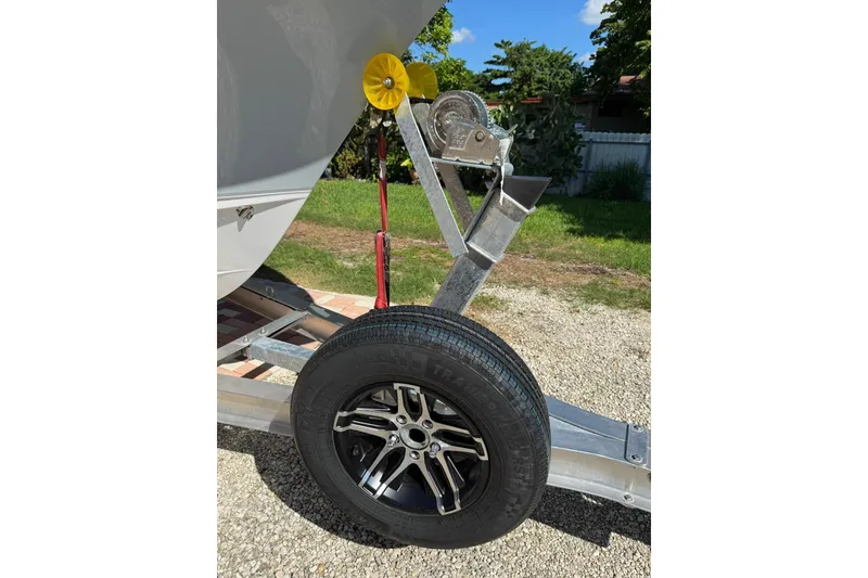 Slide: The Image of Trailer wheel and winch of 2025 Sea Hunt Ultra 239 SE boat on gravel. - 25