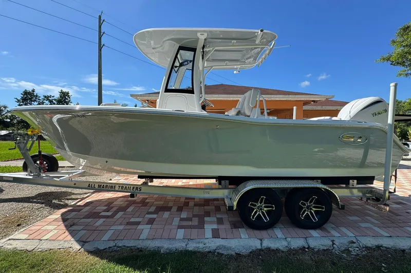 Slide: The Image of 2025 Sea Hunt Ultra 239 SE boat on trailer, parked outdoors under clear blue sky. - 3