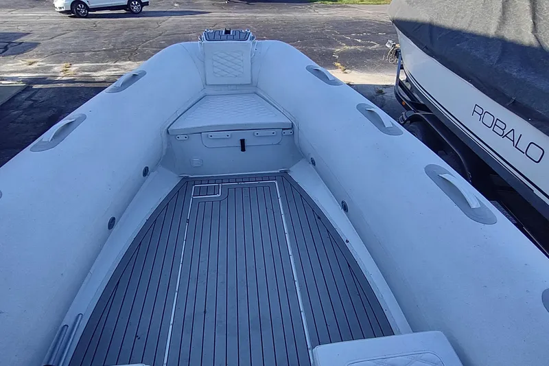 Slide: The Image of 2024 Valken 520 boat interior with gray deck and seating, parked beside a Robalo boat. - 4