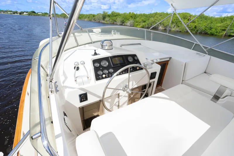 Slide: The Image of 1995 Fleming 55 yacht helm with steering wheel and navigation controls on a sunny day. - 28
