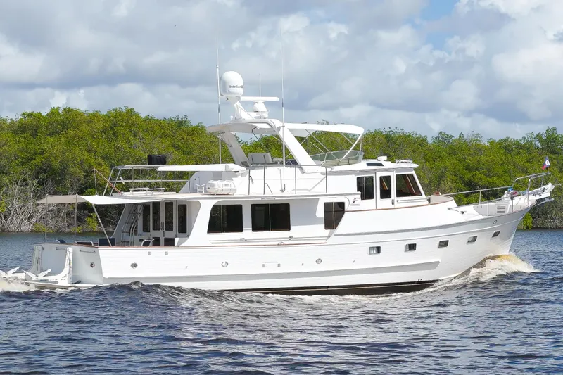 Slide: The Image of 1995 Fleming 55 yacht cruising on a river with lush green trees in the background. - 37