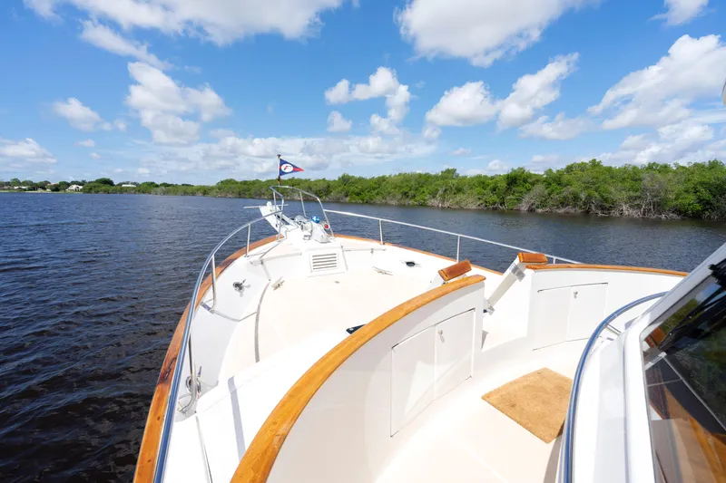 Slide: The Image of 1995 Fleming 55 yacht cruising on a serene river under a bright blue sky. - 39