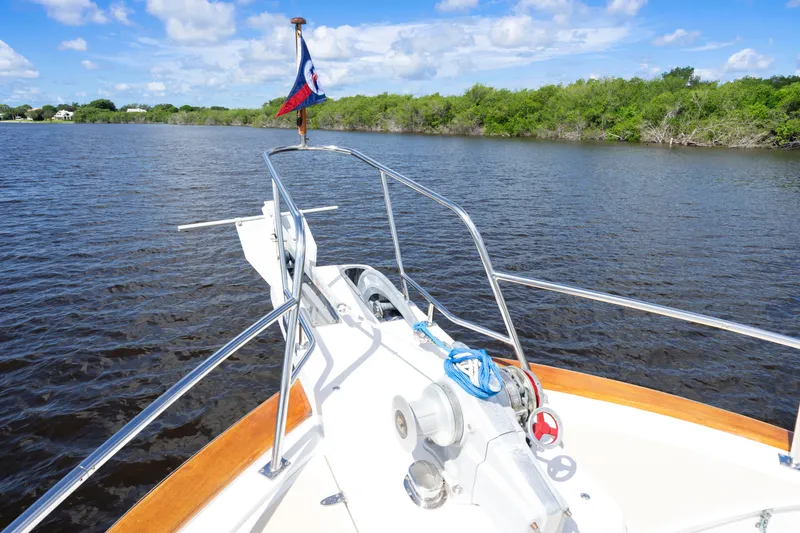 Slide: The Image of Bow of 1995 Fleming 55 yacht on calm water, clear sky, lush shoreline. - 40