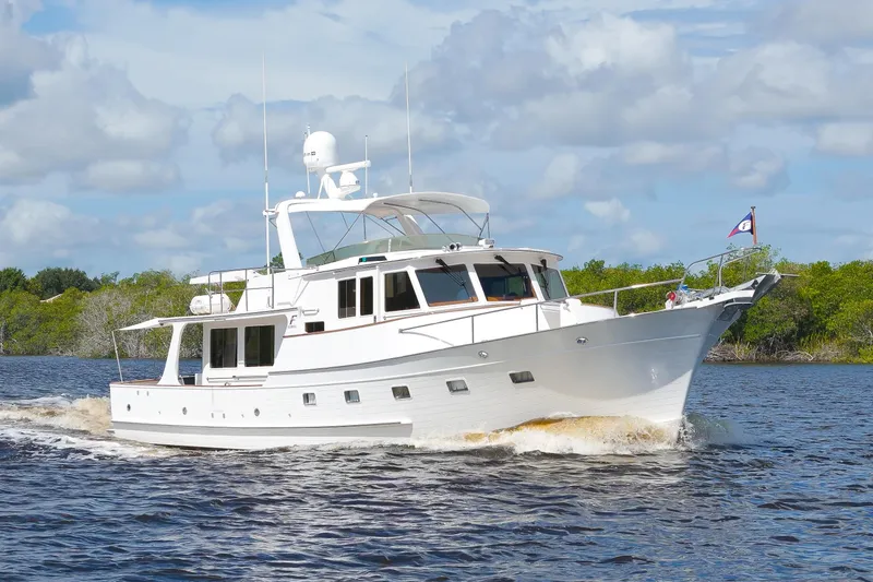 Slide: The Image of A 1995 Fleming 55 yacht cruising on a river under a partly cloudy sky. - 49