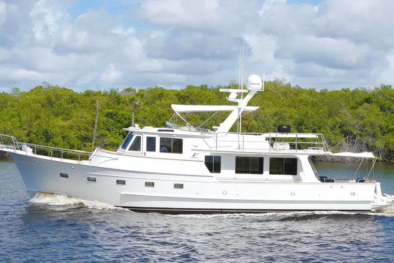 Slide: The Image of 1995 Fleming 55 yacht cruising on a river with lush green trees in the background. - 50