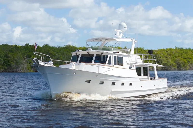Slide: The Image of Luxurious 1995 Fleming 55 yacht cruising on a scenic waterway under a clear blue sky. - 51