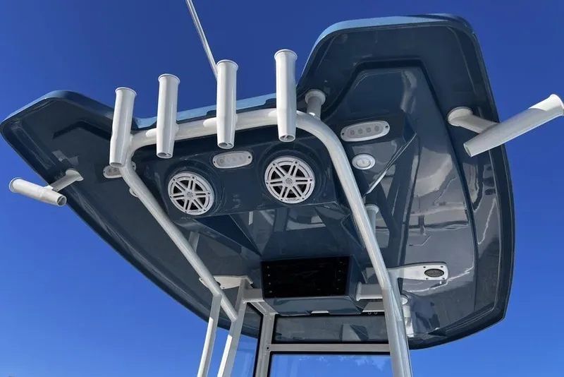 Slide: The Image of Tidewater 2300 Carolina Bay 2026 boat top view with rod holders and speakers against blue sky. - 30
