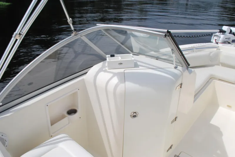 Slide: The Image of 2015 Cobia 220 Dual Console boat interior with windshield and storage compartment. - 11