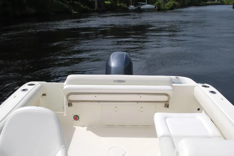 Slide: The Image of 2015 Cobia 220 Dual Console boat interior with seating, on calm water. - 15