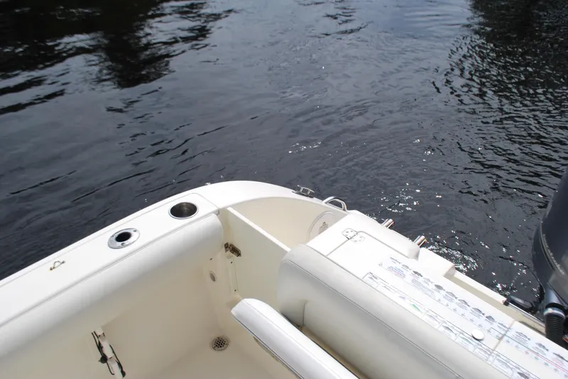 Slide: The Image of 2015 Cobia 220 Dual Console boat on water, featuring seating and fishing rod holders. - 17