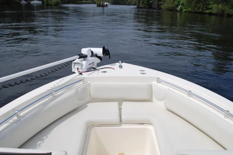 Slide: The Image of 2015 Cobia 220 Dual Console boat on calm water, featuring spacious seating and a trolling motor. - 6