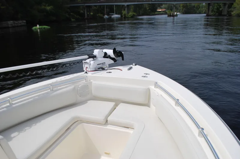Slide: The Image of 2015 Cobia 220 Dual Console boat on calm river with bridge in background. - 7