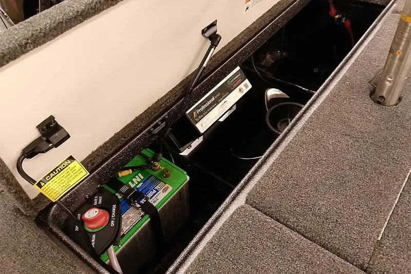 Slide: The Image of 2025 Ranger Z185 boat battery compartment with charger and safety labels. - 25