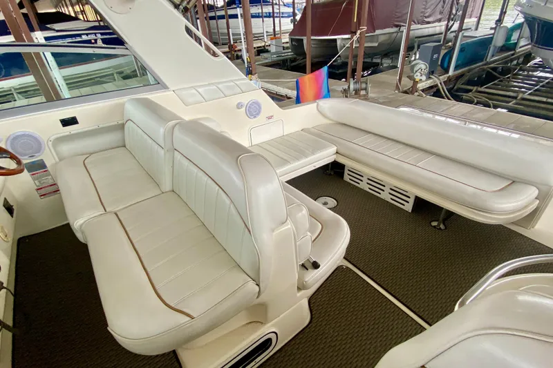 Slide: The Image of 1997 Sea Ray 330 Sundancer interior with white leather seating and table in a marina setting. - 13