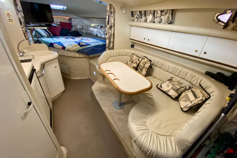 Slide: The Image of Interior of 1997 Sea Ray 330 Sundancer with cozy seating, table, and bed. - 16