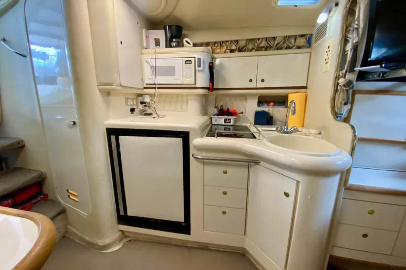 Slide: The Image of 1997 Sea Ray 330 Sundancer yacht kitchen with sink, microwave, and compact fridge. - 17