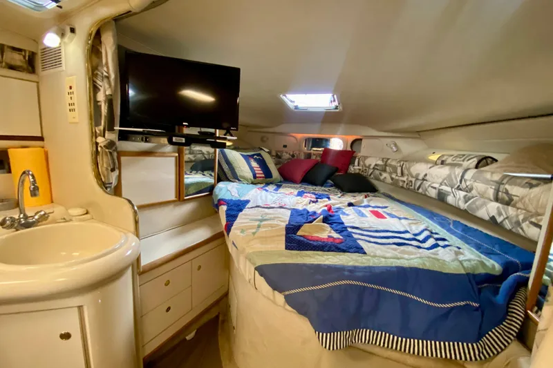 Slide: The Image of 1997 Sea Ray 330 Sundancer cabin with bed, TV, and sink. Cozy interior design. - 18