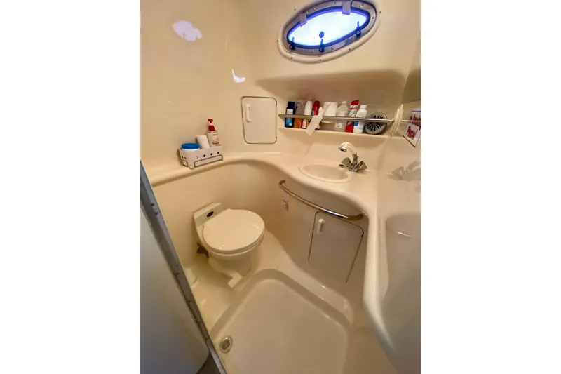 Slide: The Image of 1997 Sea Ray 330 Sundancer bathroom with toilet, sink, and storage shelves. - 23