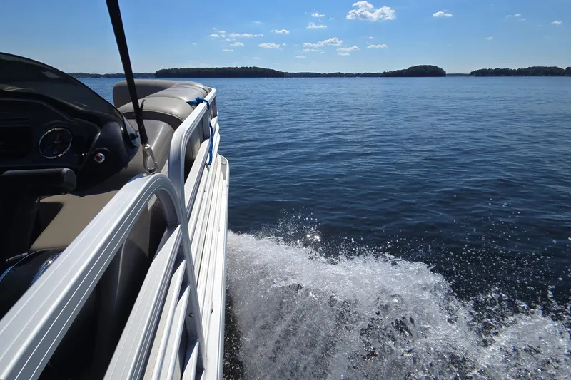 Slide: The Image of 2023 Sun Tracker Party Barge 22 RF DLX cruising on a serene lake under a clear sky. - 12
