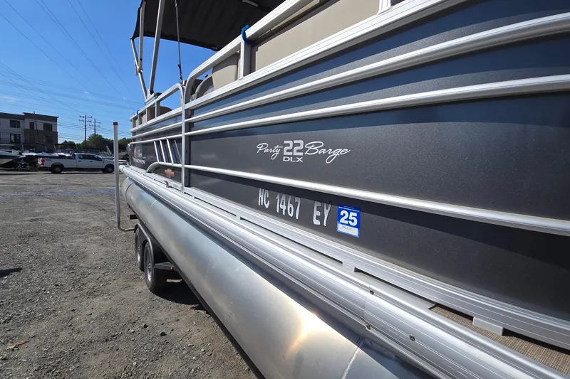 Slide: The Image of 2023 Sun Tracker Party Barge 22 RF DLX pontoon boat parked on gravel lot. - 2