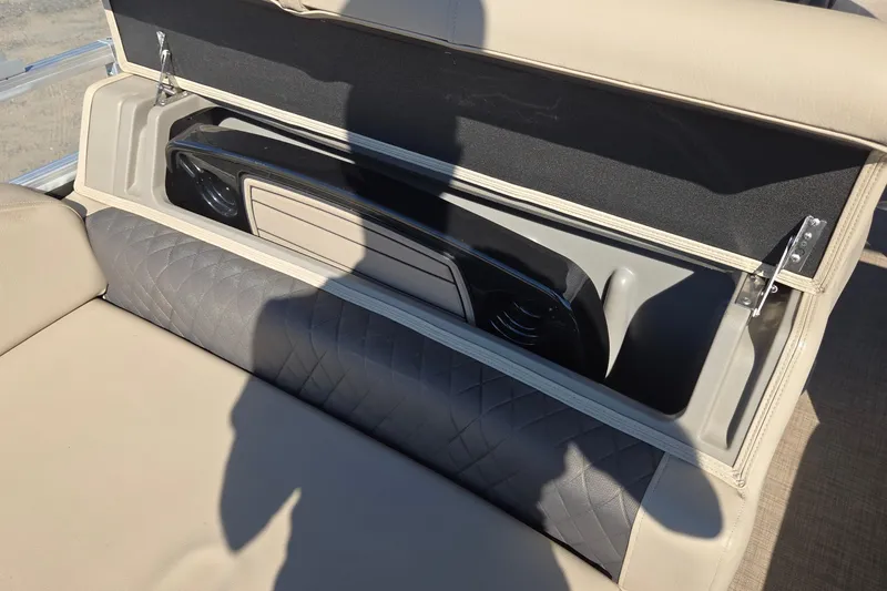 Slide: The Image of 2023 Sun Tracker Party Barge 22 RF DLX storage compartment with beige cushioned seating. - 26