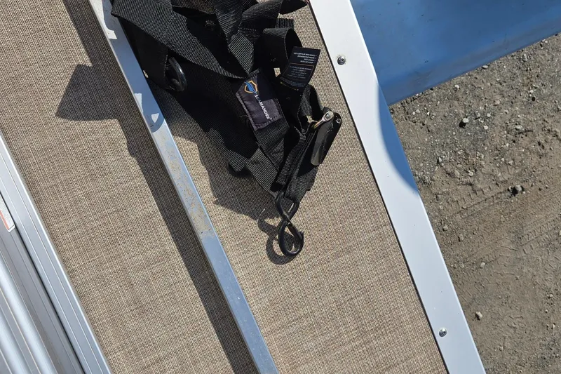 Slide: The Image of 2023 Sun Tracker Party Barge 22 RF DLX deck with black straps on textured surface. - 27