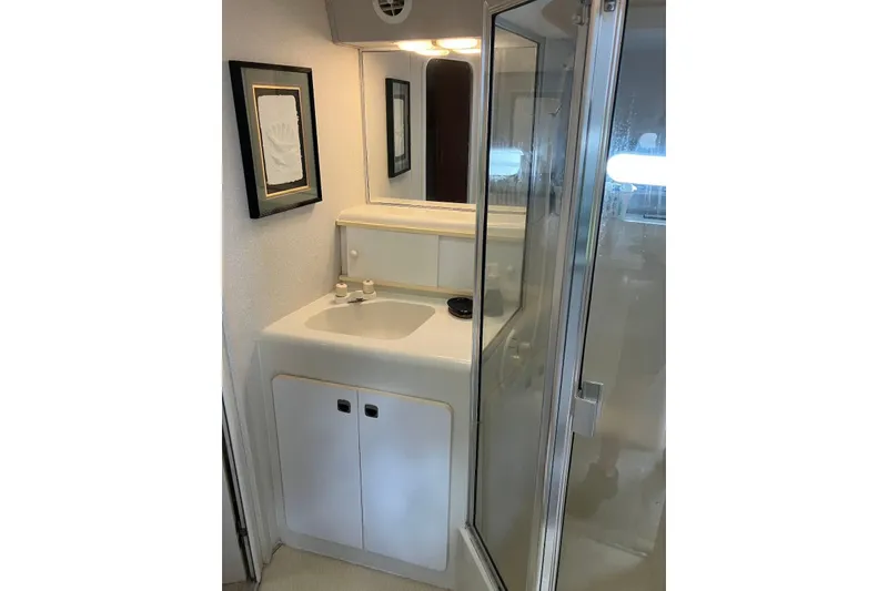 Slide: The Image of Cozy 1994 Silverton 41 Aft Cabin bedroom with nautical-themed pillows and warm lighting. - 12