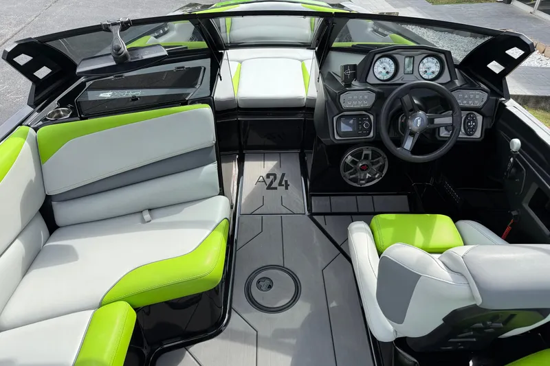 Slide: The Image of 2019 Axis A24 boat interior with green and white seating, modern dashboard, and steering wheel. - 11