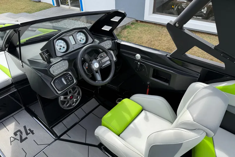 Slide: The Image of 2019 Axis A24 boat interior with green and white seating, modern dashboard, and steering wheel. - 12