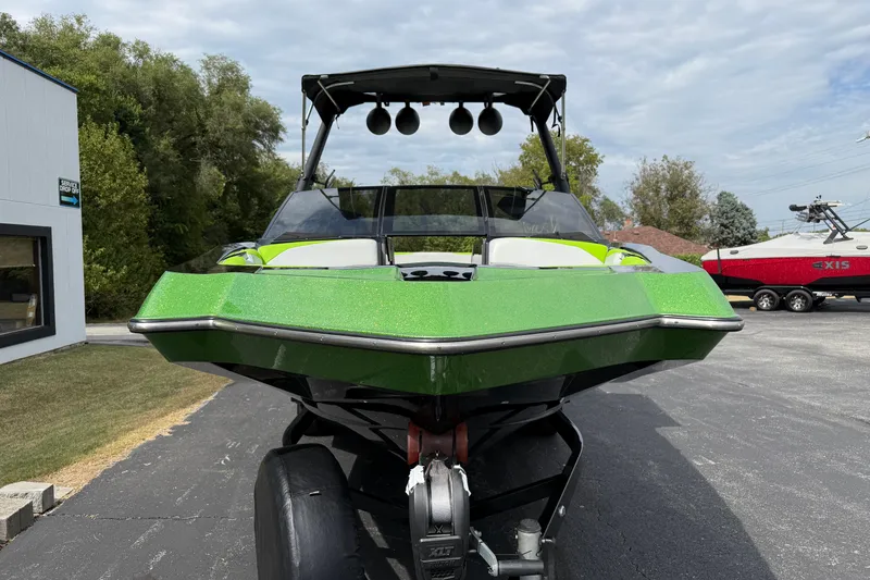 Slide: The Image of 2019 Axis A24 boat in vibrant green, parked outdoors on a sunny day. - 2
