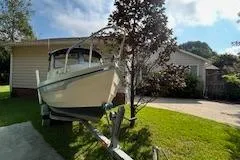 Slide: The Image of 1992 CDory 16 Cruiser boat parked in a residential driveway, surrounded by greenery. - 5