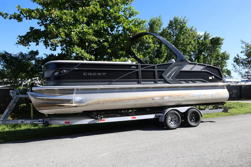 Slide: The Image of 2022 Crest Caribbean Platinum 250SLRC pontoon boat on trailer, parked outdoors. - 2