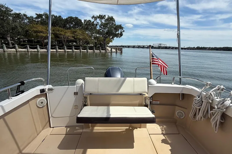 Slide: The Image of 2017 Ranger Tugs R-23 boat deck with seating, American flag, and scenic waterfront view. - 10