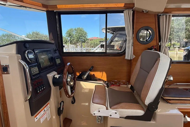 Slide: The Image of 2017 Ranger Tugs R-23 helm with steering wheel, navigation controls, and comfortable seating. - 24