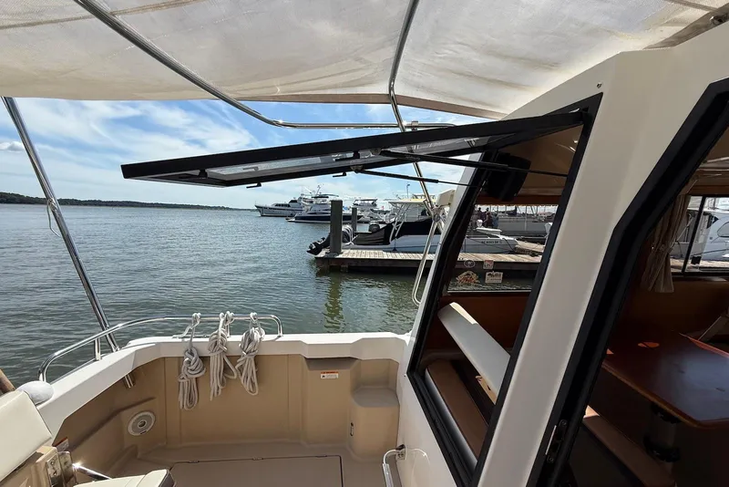 Slide: The Image of 2017 Ranger Tugs R-23 boat docked, featuring open cabin and scenic marina view. - 6