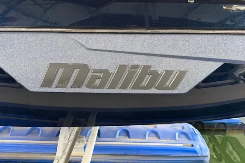 Slide: The Image of 2021 Malibu Wakesetter 25 LSV boat logo on hull, docked on water. - 16