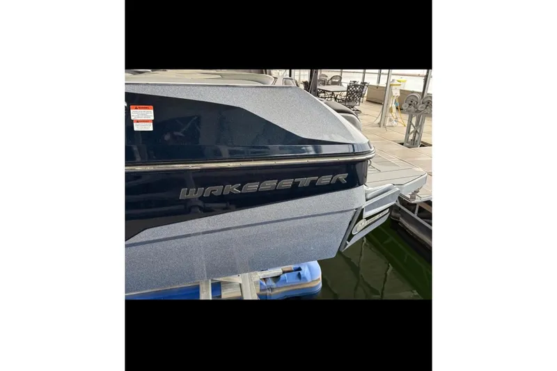 Slide: The Image of 2021 Malibu Wakesetter 25 LSV boat docked, showcasing sleek design and branding. - 17