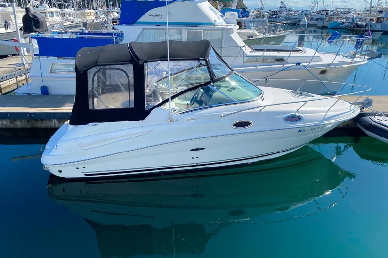 The Image of 2006 Sea Ray 240 Sundancer boat docked in a marina, featuring a black canopy. - 0