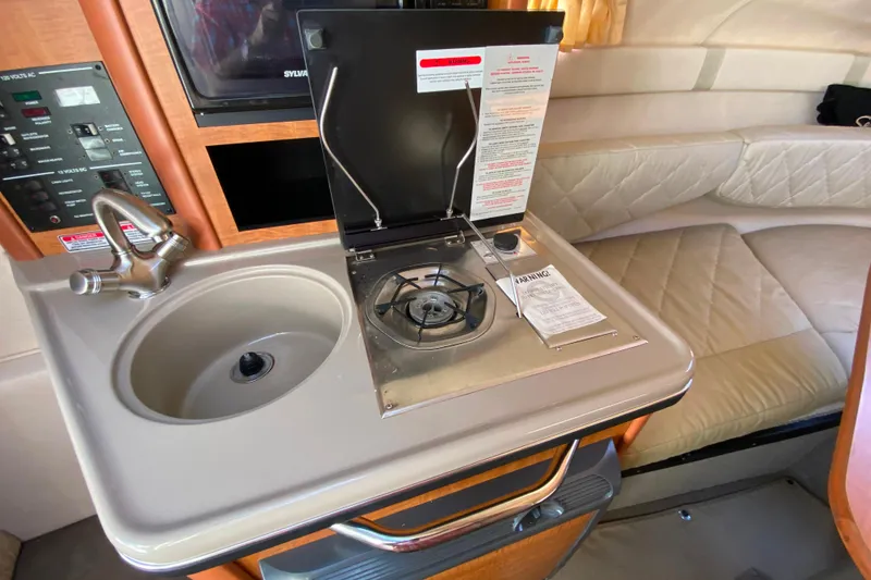 Slide: The Image of 2006 Sea Ray 240 Sundancer interior with kitchenette, sink, stove, and seating area. - 18