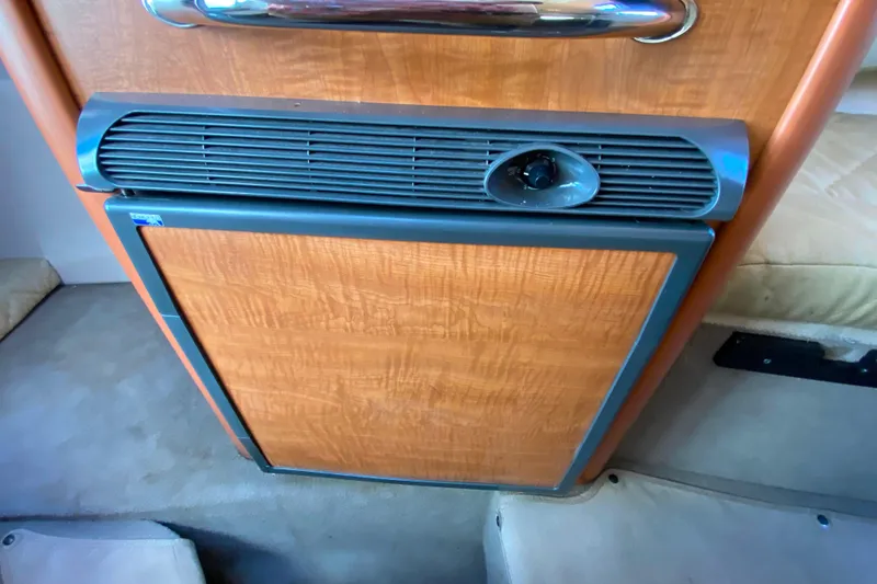 Slide: The Image of 2006 Sea Ray 240 Sundancer cabin interior with wood paneling and compact fridge. - 21