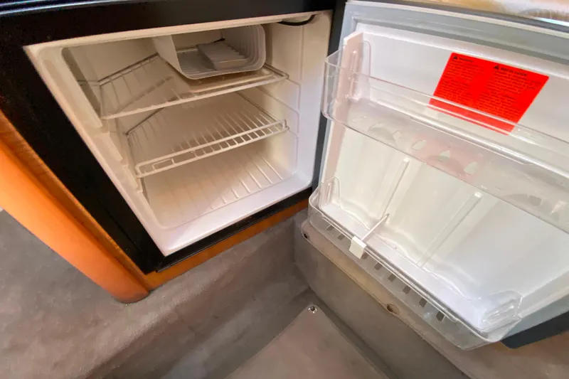 Slide: The Image of Open refrigerator inside 2006 Sea Ray 240 Sundancer boat, showing empty shelves and door storage. - 22