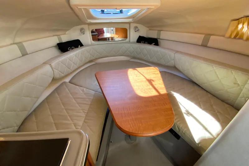 Slide: The Image of Interior of 2006 Sea Ray 240 Sundancer with cozy seating and wooden table. - 23
