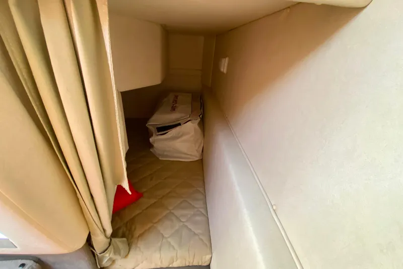 Slide: The Image of 2006 Sea Ray 240 Sundancer cabin interior with bed and storage bag. - 27